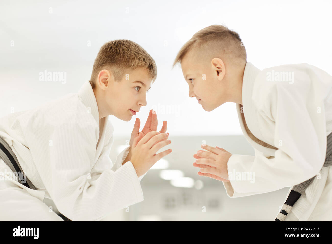 Due ragazzini in kimono in piedi di fronte a ogni altro e la pratica di scioperi nel karate Foto Stock