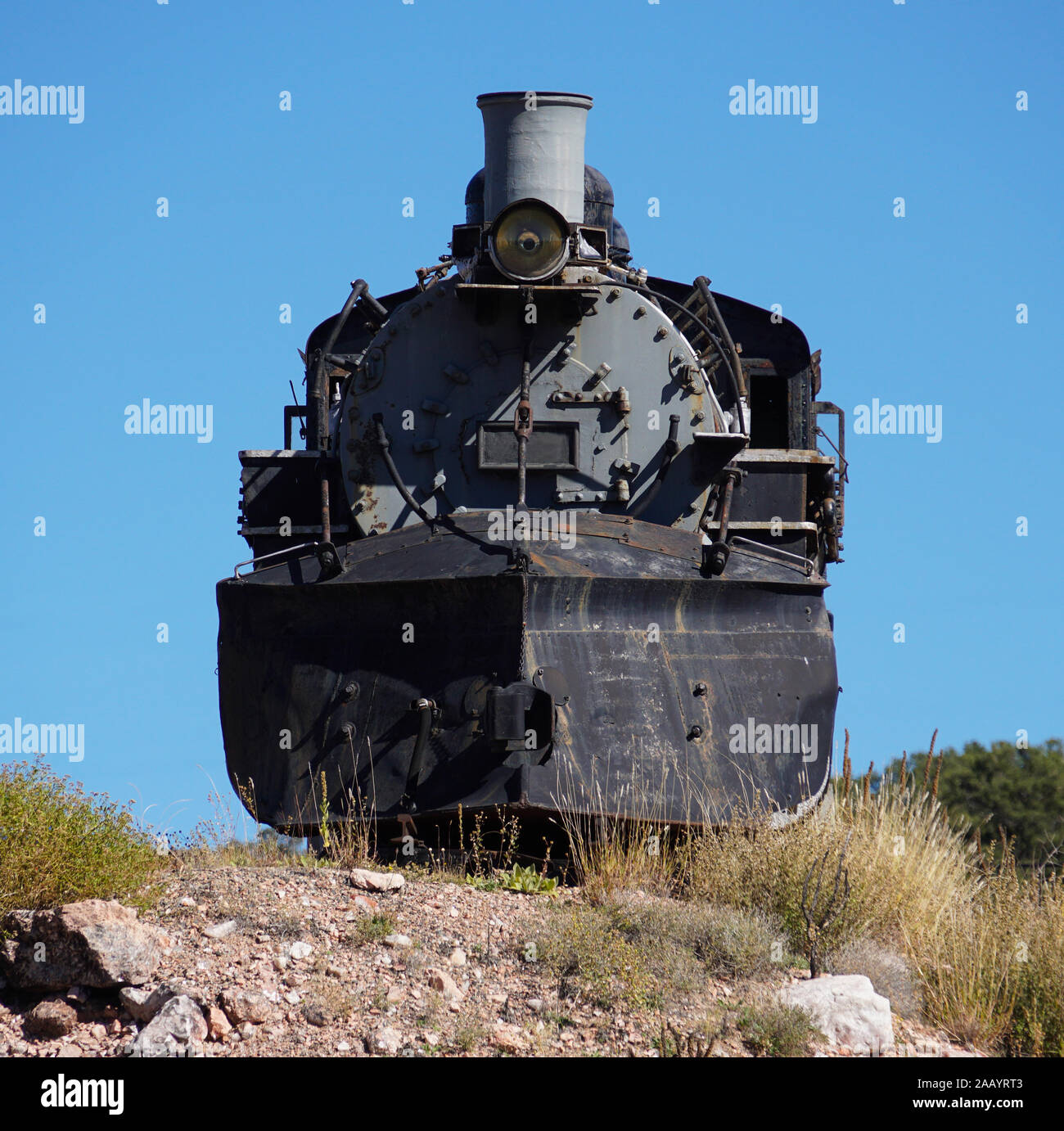 Una vecchia locomotiva a vapore sito motore tranquillamente nel deserto con un cielo blu brillante background. Foto Stock