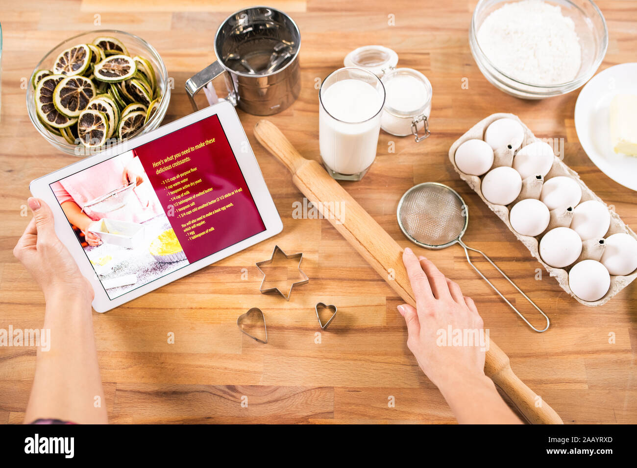 Disposizione piatta delle mani del giovane casalinga azienda tablet e matterello mentre andando per cuocere pasta a casa Foto Stock
