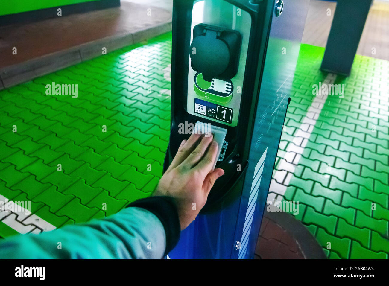 Un uomo paga per la ricarica di un auto elettrica. Mano azienda catd a pagare alla stazione di carica. Concetto di elettricità verde, ambiente pulito, emissione Foto Stock