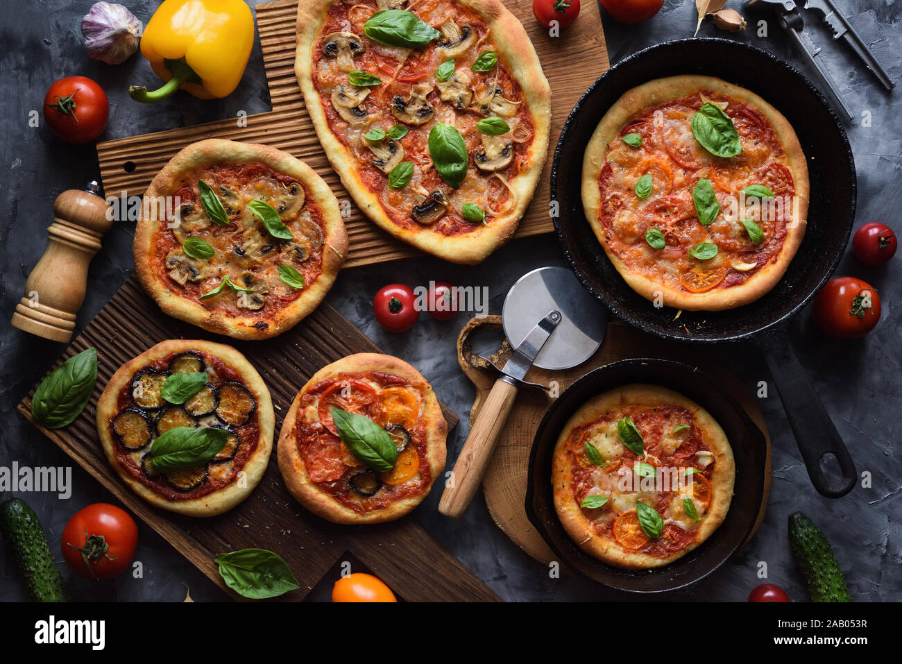 Una sana alimentazione vegetariana flatlay. In casa pizze rustiche con pomodori e funghi, melanzane e basilico con ingredienti grezzi in ghisa padelle e rovere b Foto Stock