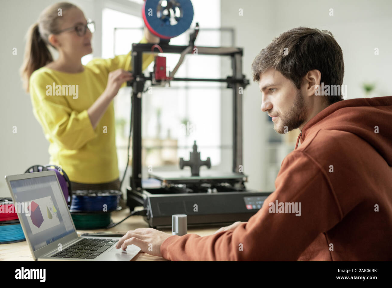Uomo serio concentrare sul lavoro su nuovi oggetti sullo sfondo del suo collega lo stelo di controllo sulla stampante 3D Foto Stock