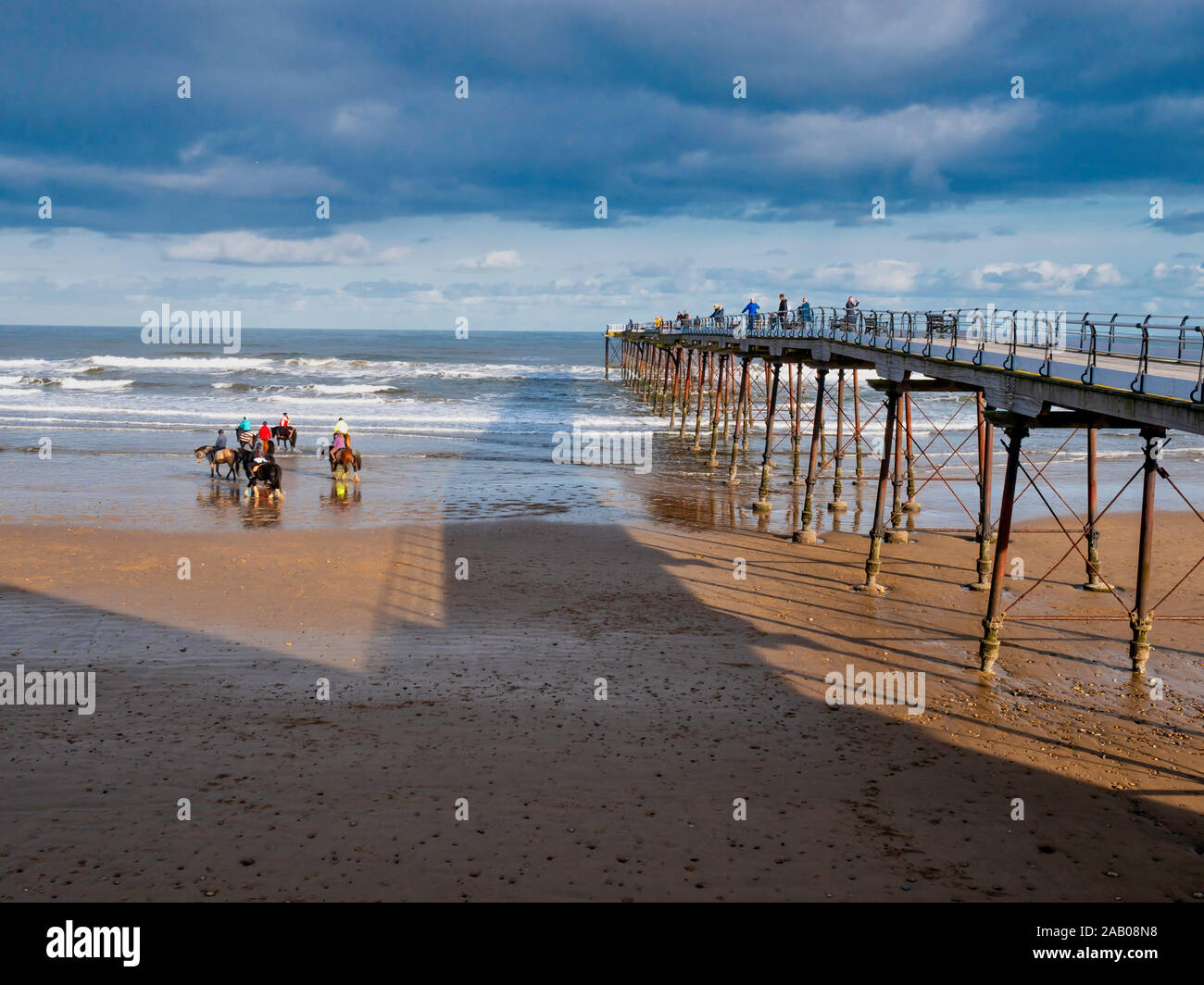 Saltburn dello Yorkshire settentrionale della costa del Mare del Nord la gente sul molo a guardare i piloti a cavallo sulla spiaggia Foto Stock