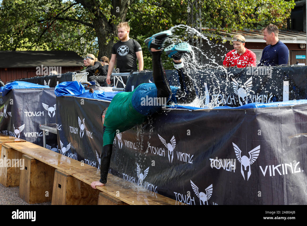 Vichingo dura corsa a ostacoli partecipante salta fuori di acqua ghiacciata in piscina a Helsinki, Finlandia Foto Stock