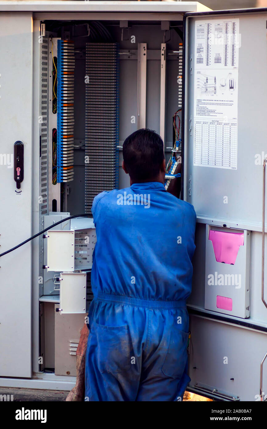 Lavoratore elettricista in blu abiti da lavoro controllo casella di trasformazione su strada Foto Stock