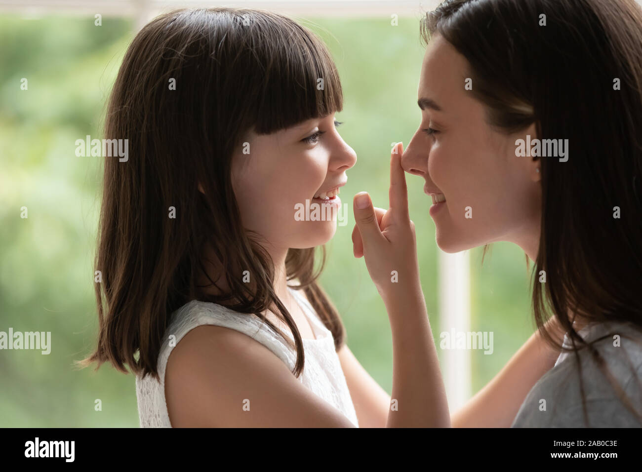 Piccola figlia toccare naso di amare la mamma che mostra l'amore Foto Stock