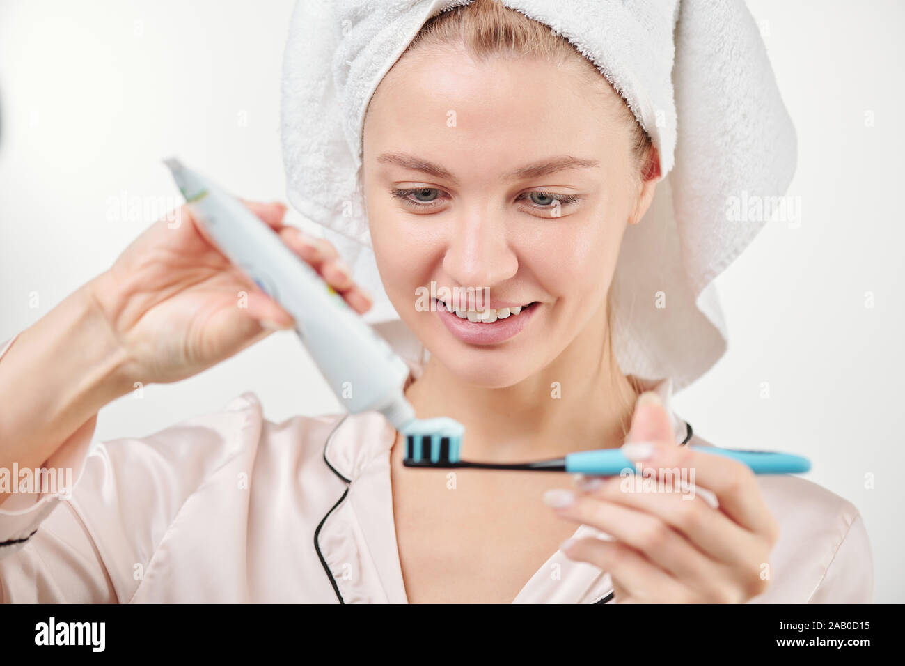 Sano giovane donna applicando una pasta dentifricia su uno spazzolino da denti prima di spazzolare i denti Foto Stock