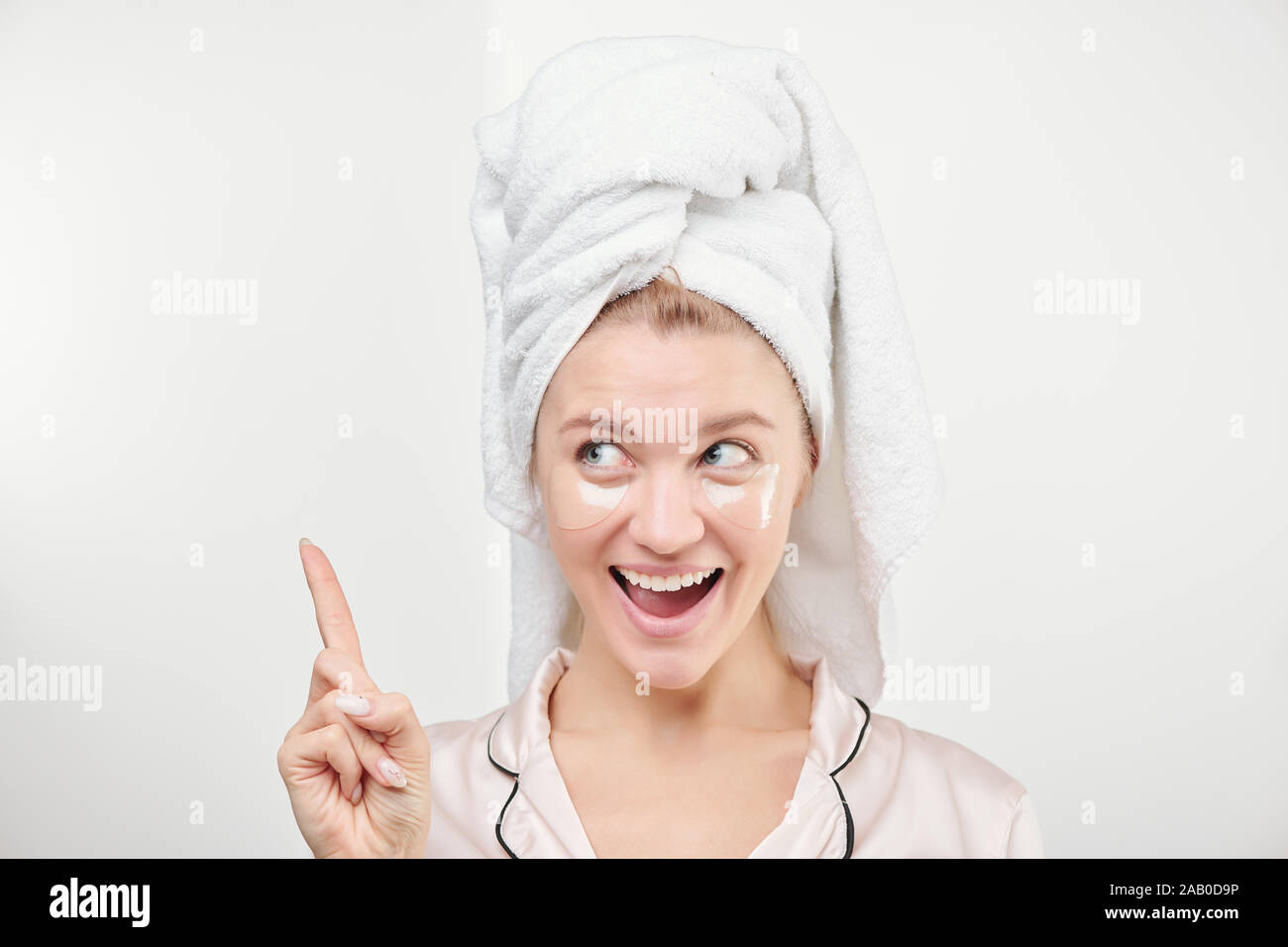 Felice bella donna con sotto-eye patch sul viso e asciugamano sulla testa Foto Stock