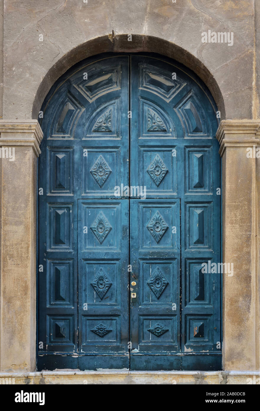 Sfondo con un vecchio e storico e stagionato in legno di colore blu, porta in un muro di pietra con un arco a tutto sesto e in Sicilia, Italia Foto Stock