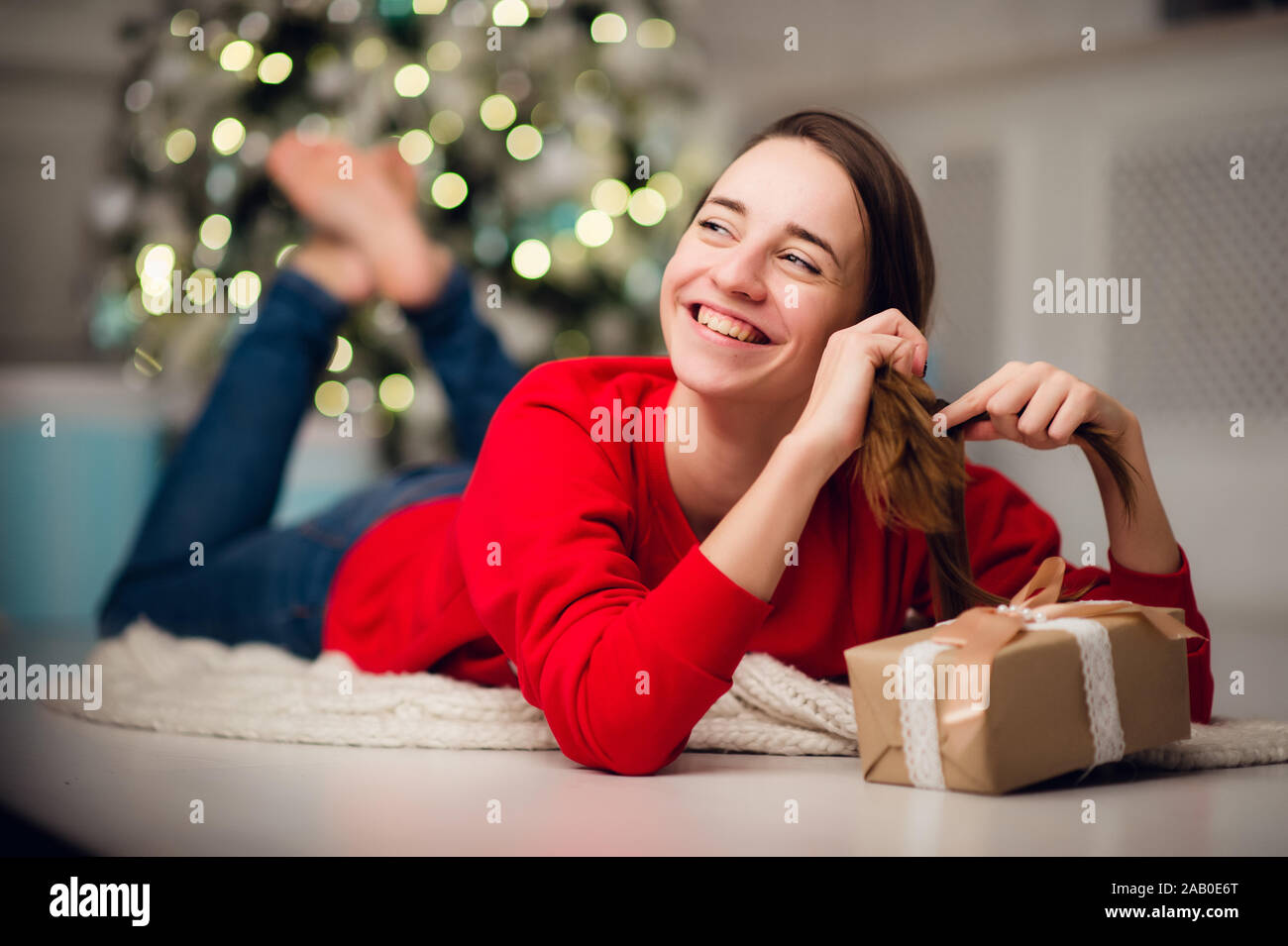 Basso angolo di seguito visualizza foto di affascinanti carino bella ragazza attraente con un regalo che indossa jeans e maglione rosso Foto Stock