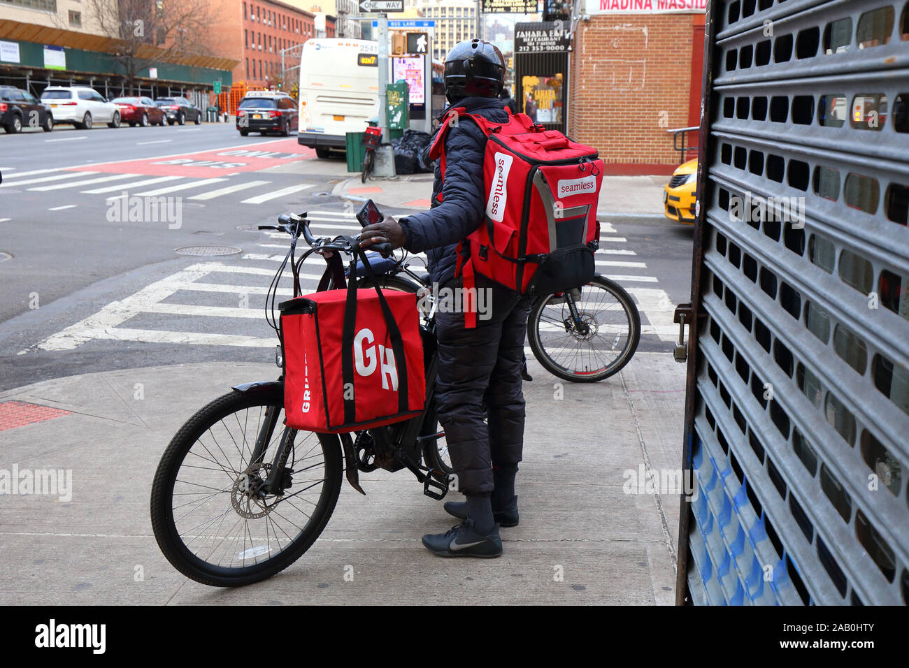Un ciclista per la consegna di alimenti che trasporta sacchetti con isolamento termico senza cuciture e GRUB Hub a New York City Foto Stock