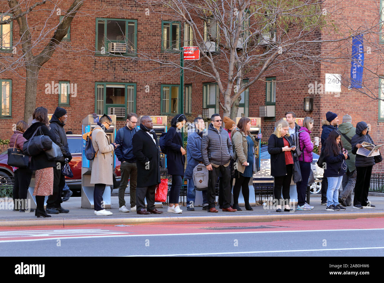 Persone in attesa a una fermata dell'autobus sul lato est di Manhattan alla fine della coda dell'ora di punta del mattino, New York, NY (21 novembre 2019) Foto Stock