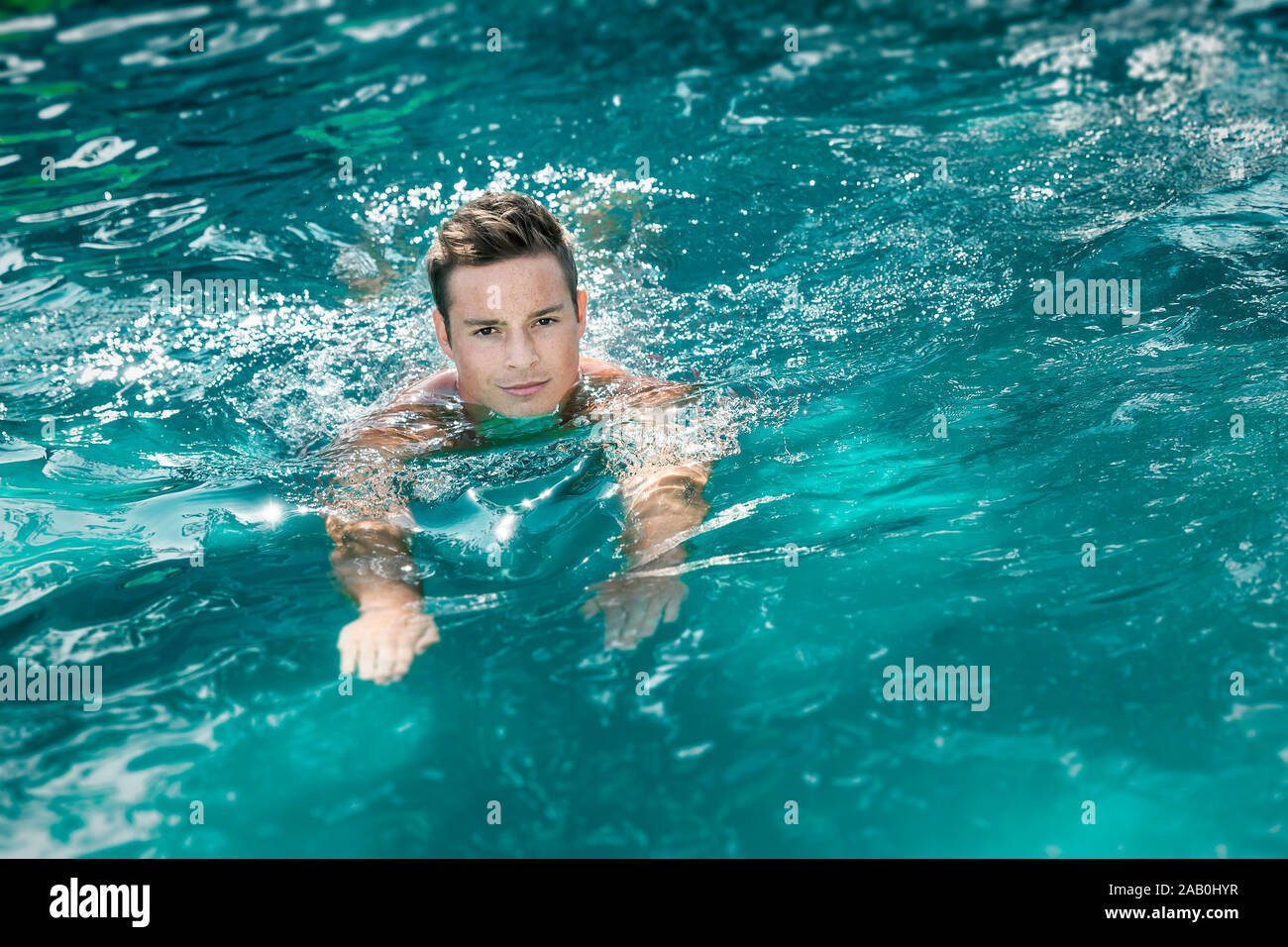 Ein junger Mann, der im Schwimmbecken schwimmt Foto Stock