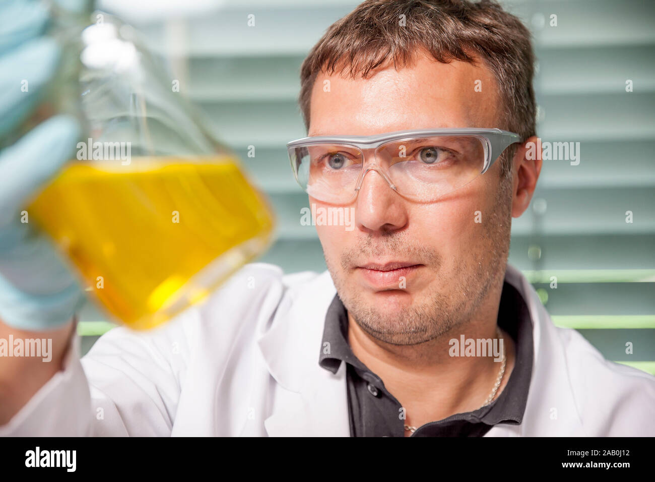 Ein junger Laborant, der mit Chemikalien experimentiert Foto Stock