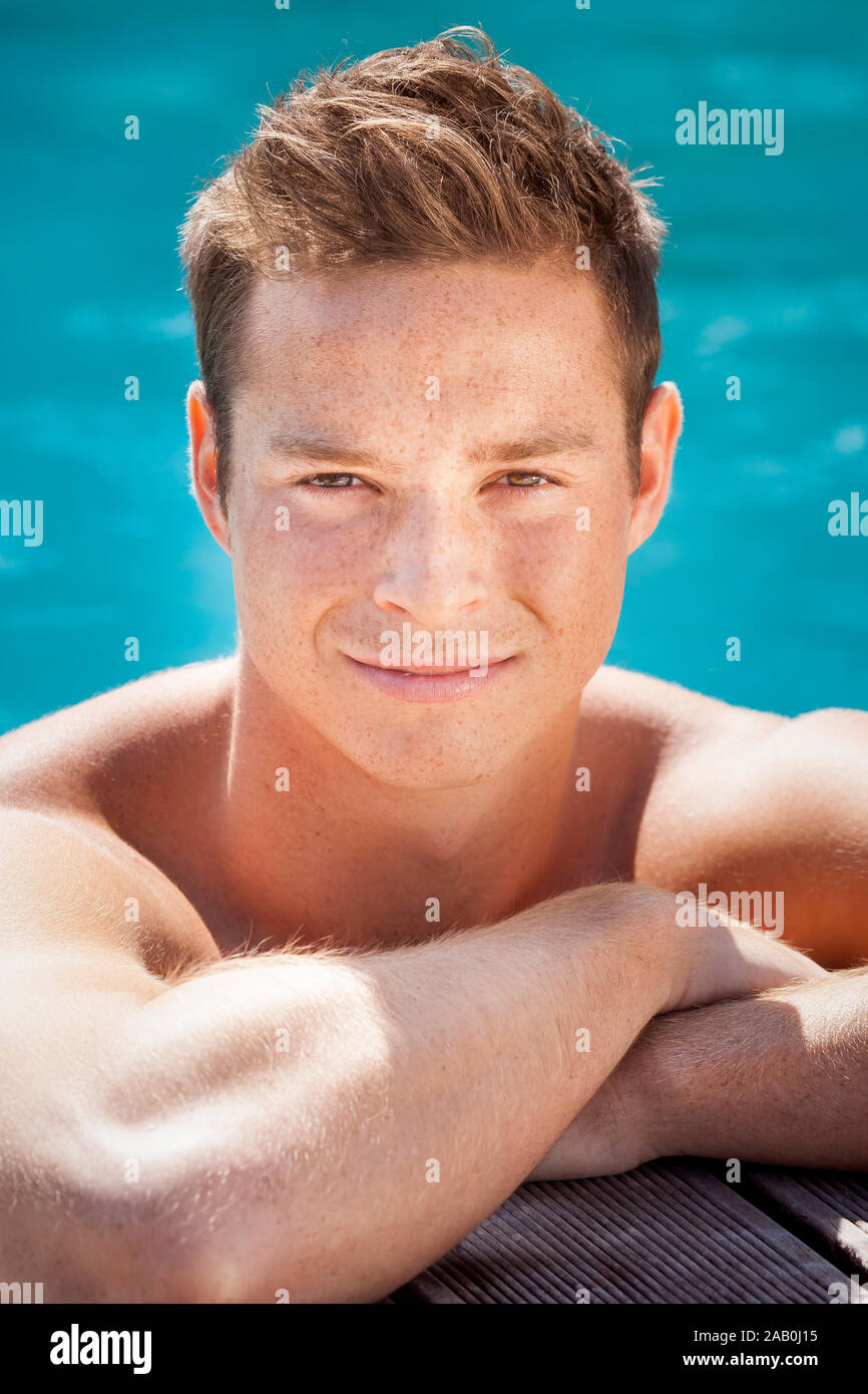Ein freundlicher junger Mann, der im Schwimmbecken entspannt Foto Stock