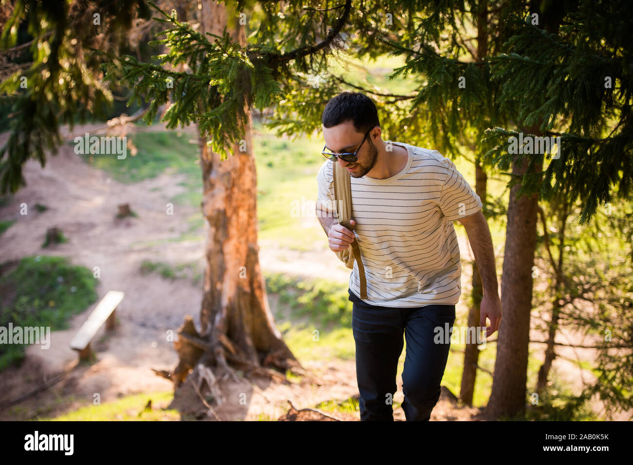 Felice l'uomo barbuto viaggiatore con zaino a piedi nella foresta. Turismo, Viaggi Avventura, escursione concetto - sorridente giovane uomo a camminare con zaino in Foto Stock