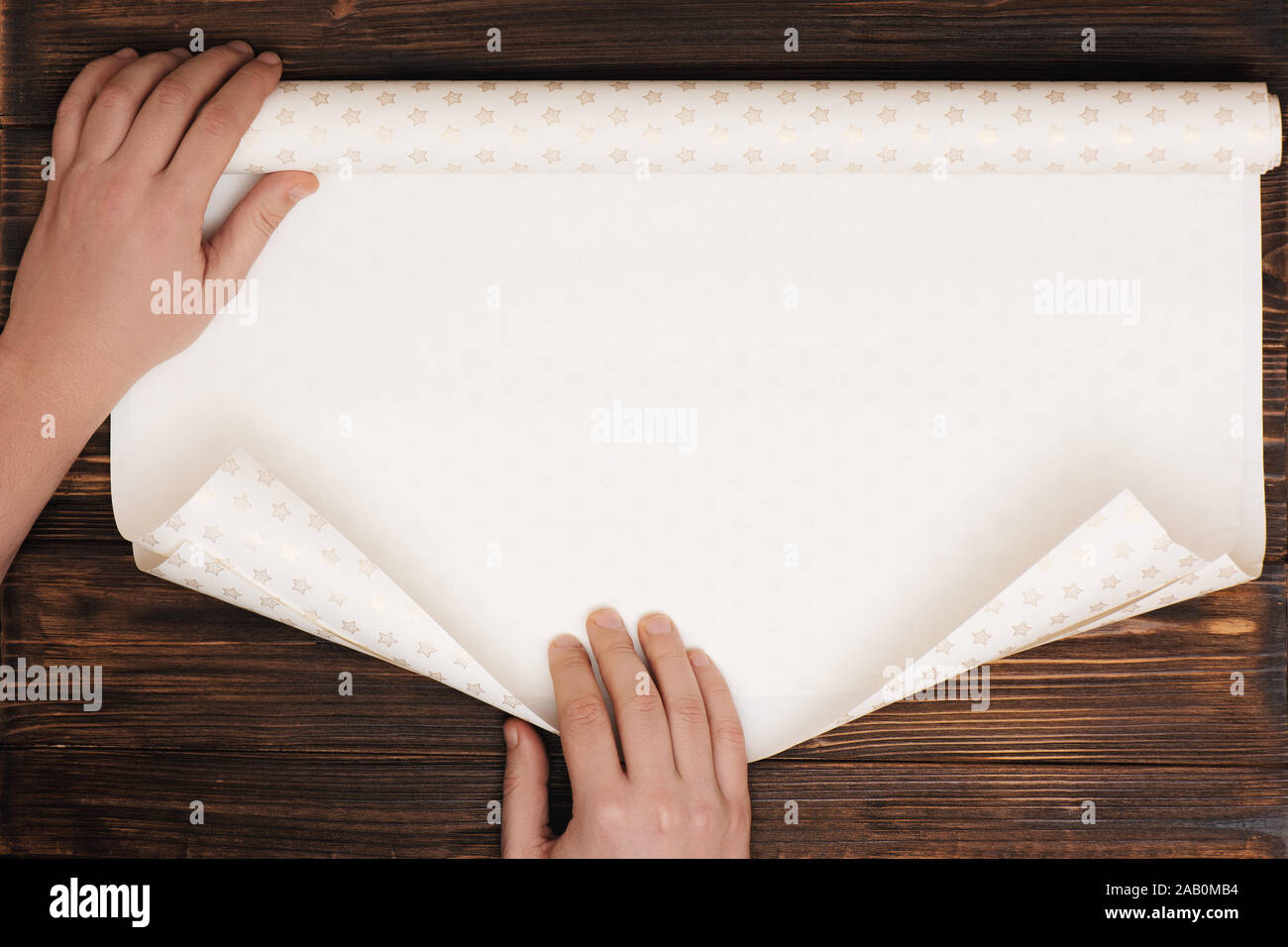 Le Mans le mani piegando la carta per avvolgere presente su sfondo di legno con copia spazio. Foto Stock