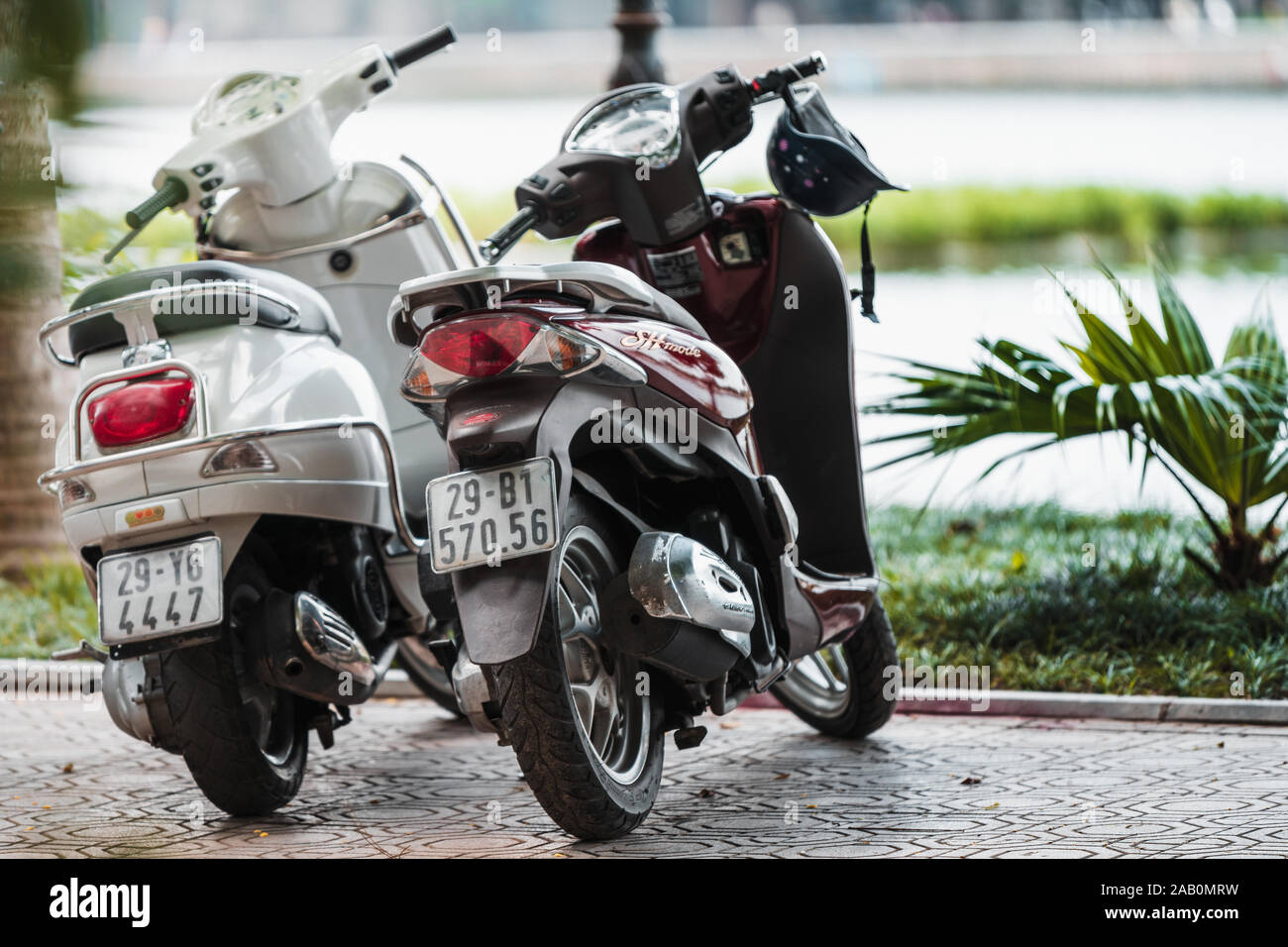 Hanoi, Vietnam - 11 Ottobre 2019: due scooters stand in una linea di Hanoi nella parte anteriore di un grande lago in una giornata di sole. Foto Stock