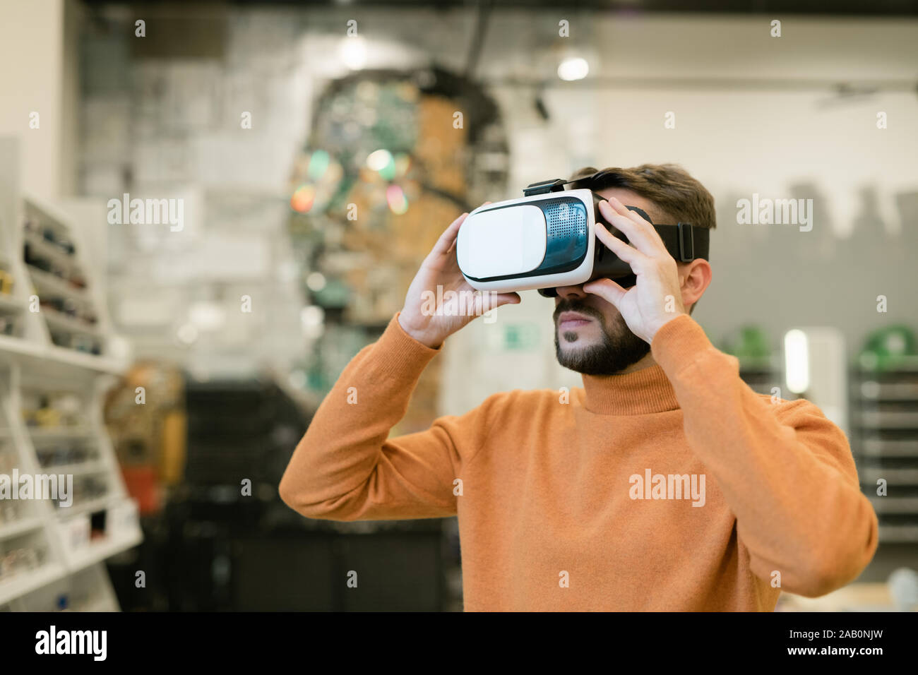 Barbuto giovane uomo che indossa le cuffie vr all'interno contemporaneo negozio OTTICA Foto Stock