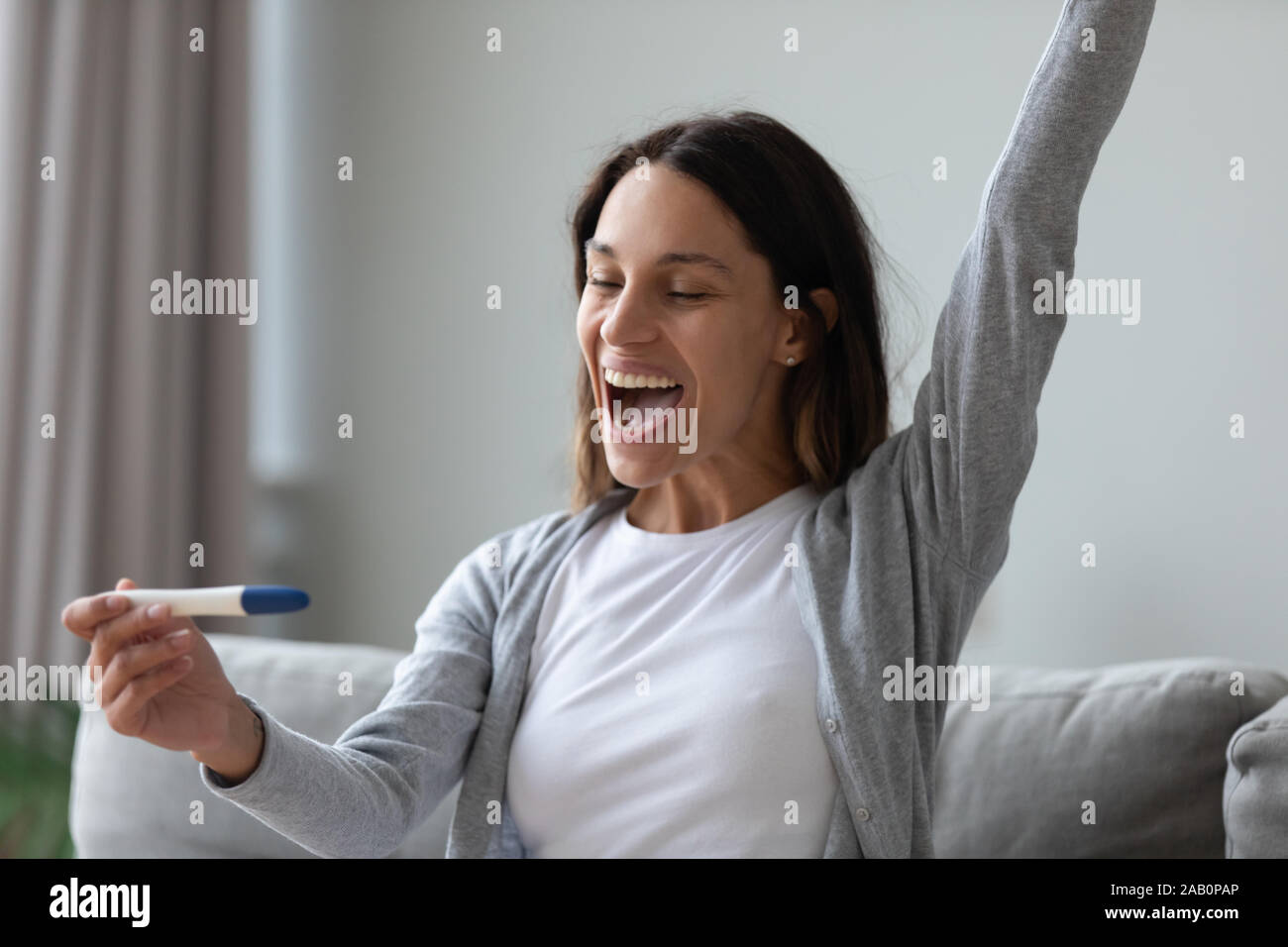 Donna utilizzare test di gravidanza di vedere due strisce celebrando si sente felice Foto Stock