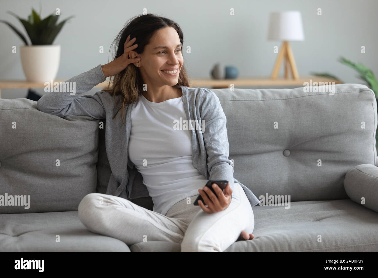 Bella donna trascorrere weekend pigro seduto sul lettino con lo smartphone Foto Stock