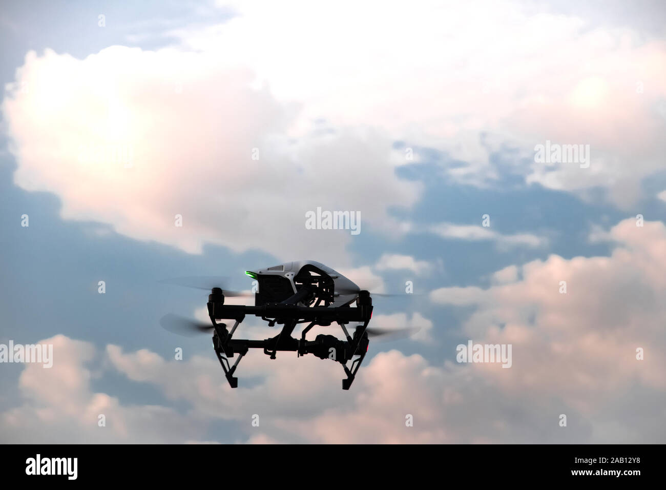 Un quadrocopter nera con una fotocamera digitale vola in un cielo nuvoloso. Unmanned Aerial drone con eliche contro lo sfondo di Nuvole rosa e blu s Foto Stock