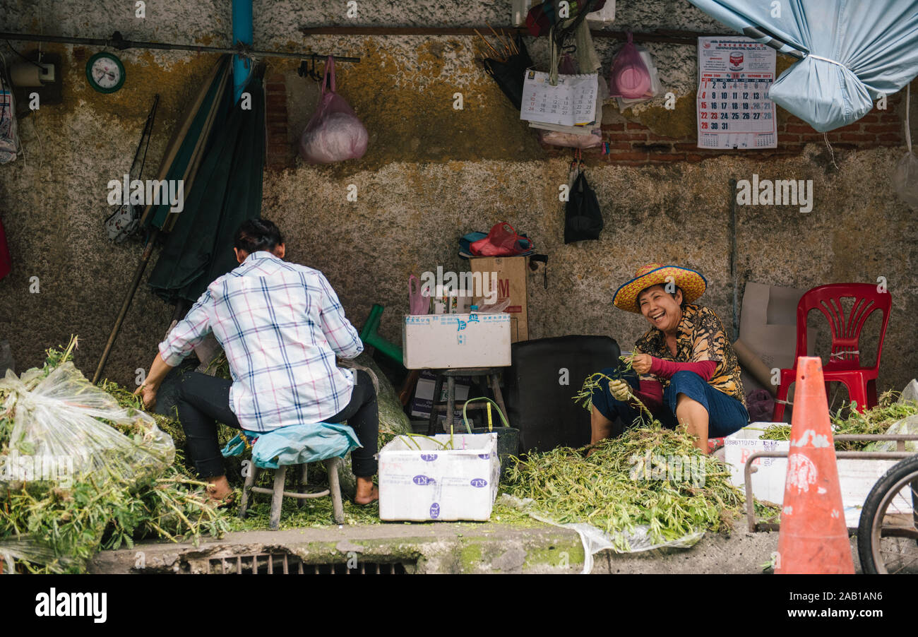 Vecchia donna in Bangkok lavori sulla strada vegtables di smistamento Foto Stock