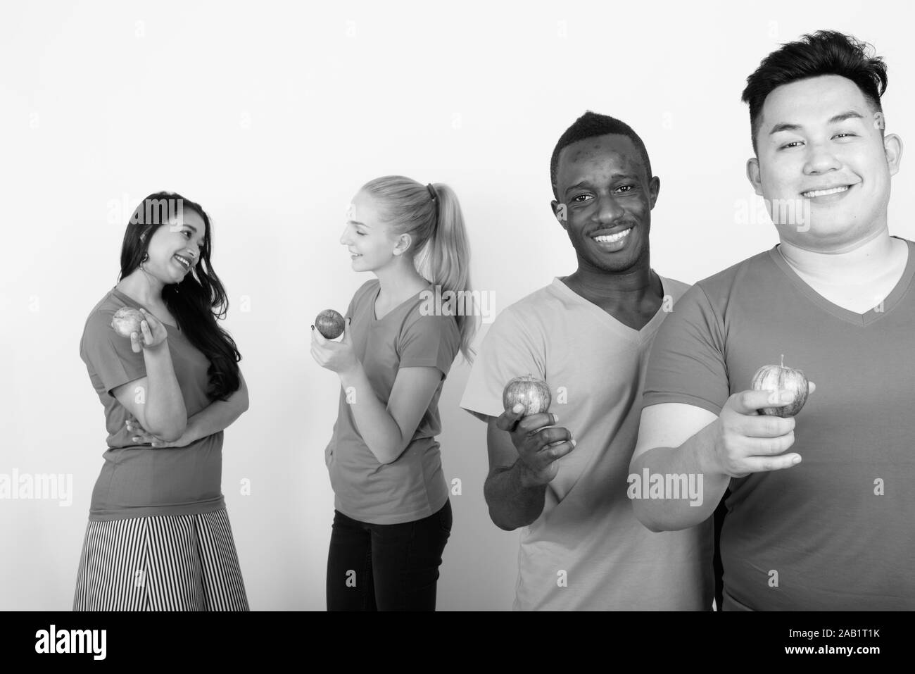 Studio shot di felice variegato gruppo di multi etnico sorridente amici tenendo red apple insieme con gli amici a parlare nel retro Foto Stock