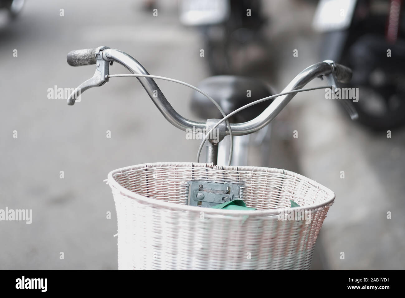 Vecchia bicicletta con una fatta a mano cesto di paglia su una strada di città Foto Stock Vecchia bicicletta con una fatta a mano cesto di paglia su una strada di città Foto Stock