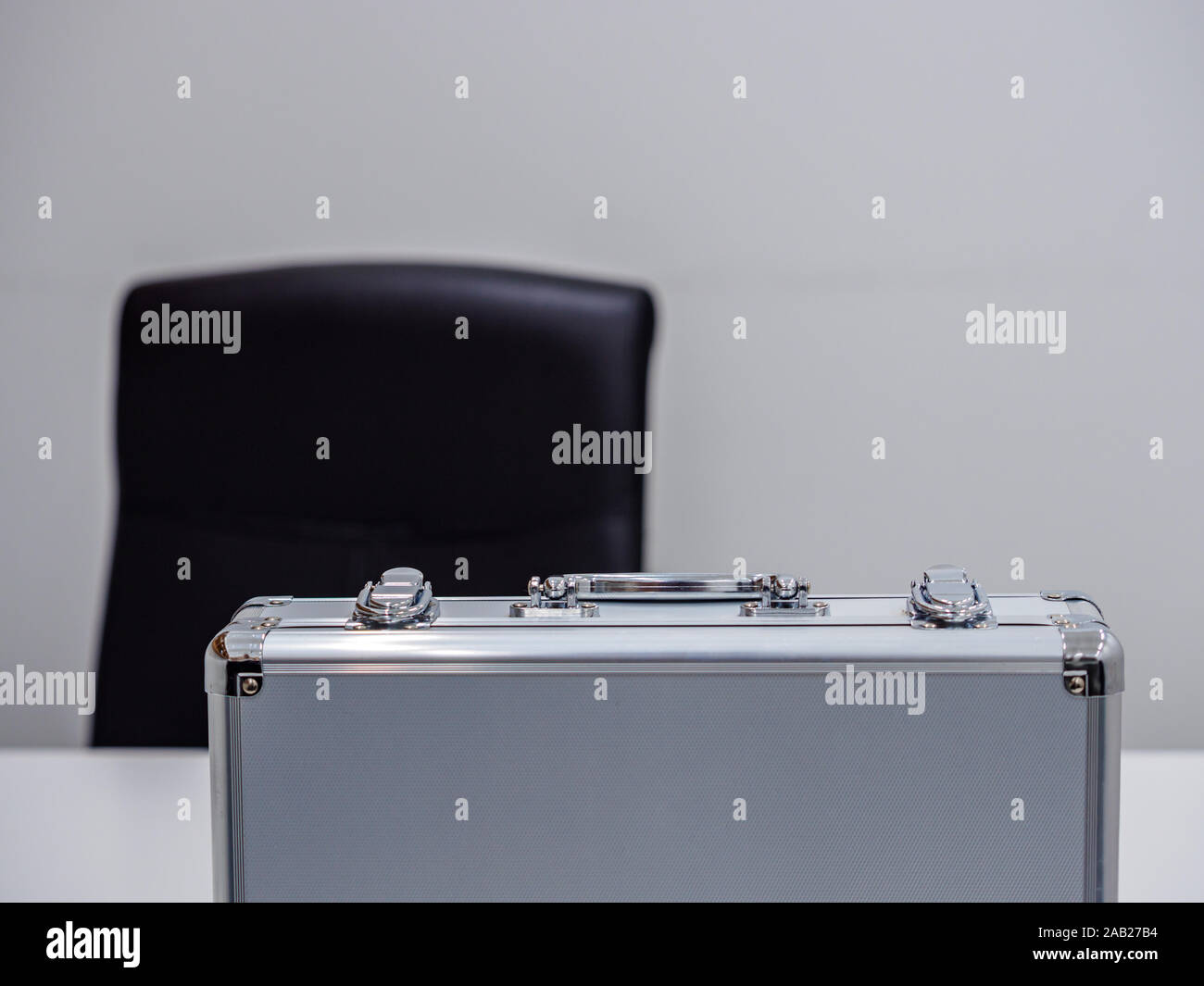 Un montante di alluminio valigetta metallica su un tavolo in un ambiente d'ufficio. Affare / contanti il concetto di transazione Foto Stock