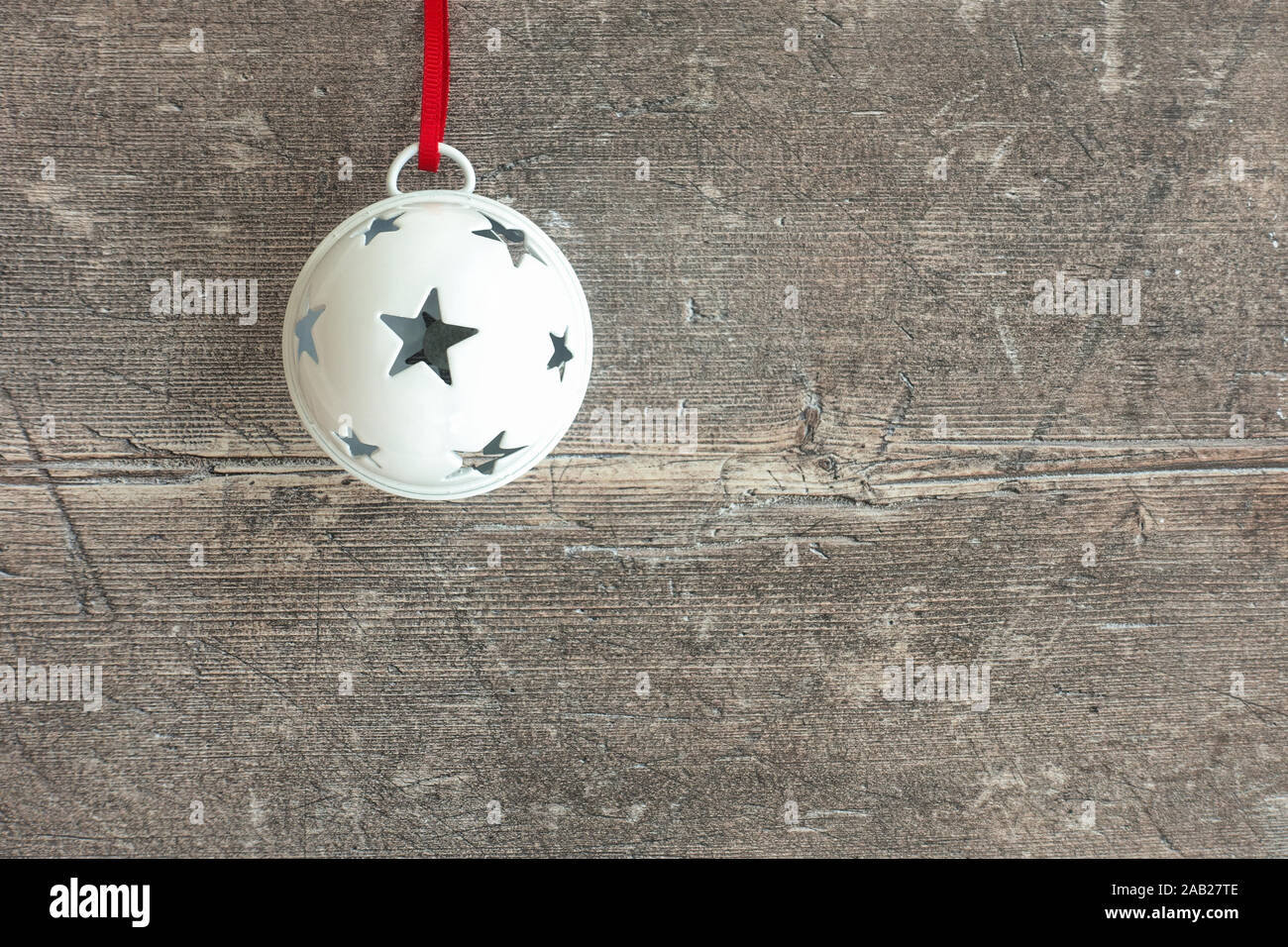 Primo piano di un bianco appeso jingle bell sul marrone scuro, rustico in legno stagionato con copia spazio. Vista dall'alto. Foto Stock