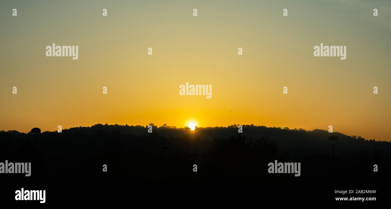 Tramonto sulla montagna. Colline coperte di olivi, silhouette nera contro arancione chiaro colore sfondo del cielo Foto Stock