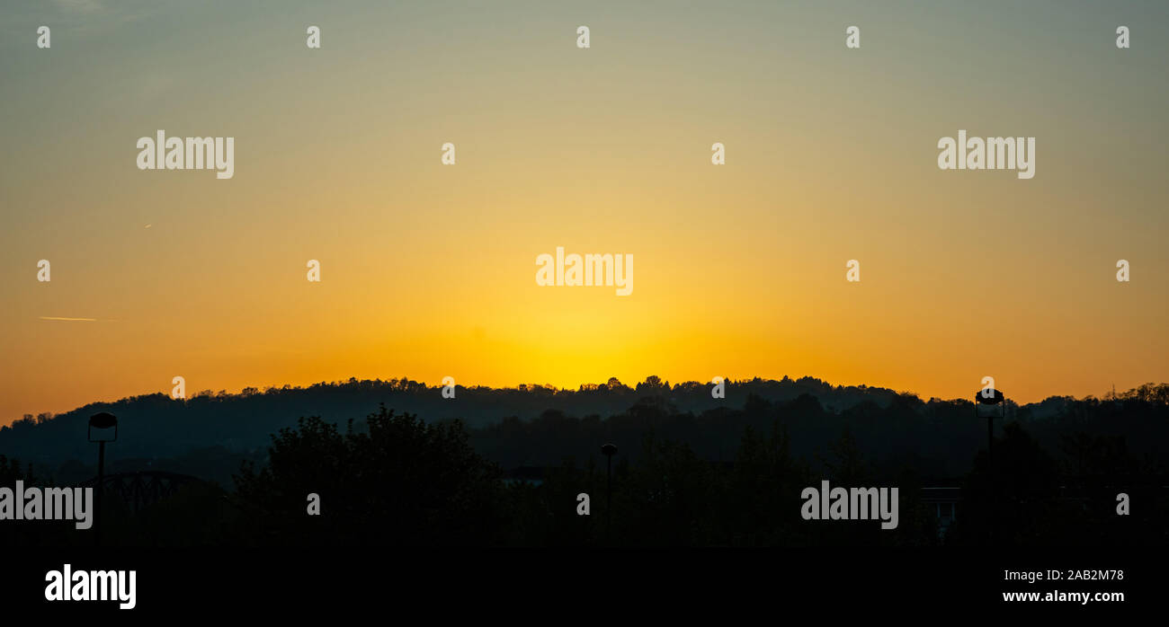 Tramonto sulla montagna. Colline coperte di olivi, silhouette nera contro arancione chiaro colore sfondo del cielo Foto Stock