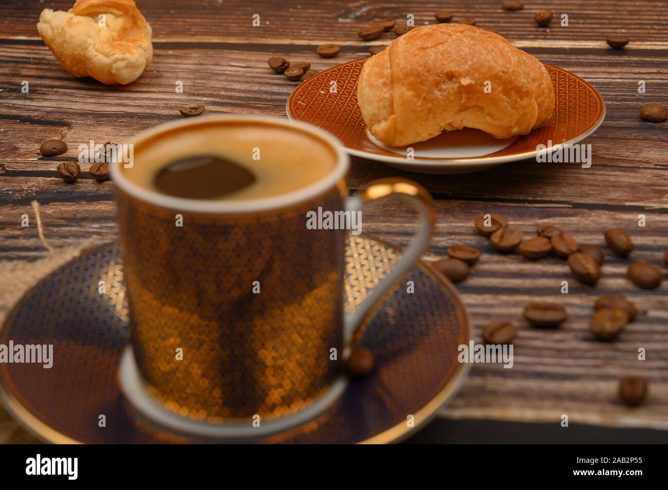 Tazza da caffè, croissant e caffè in grani su sfondo di legno. Close up Foto Stock