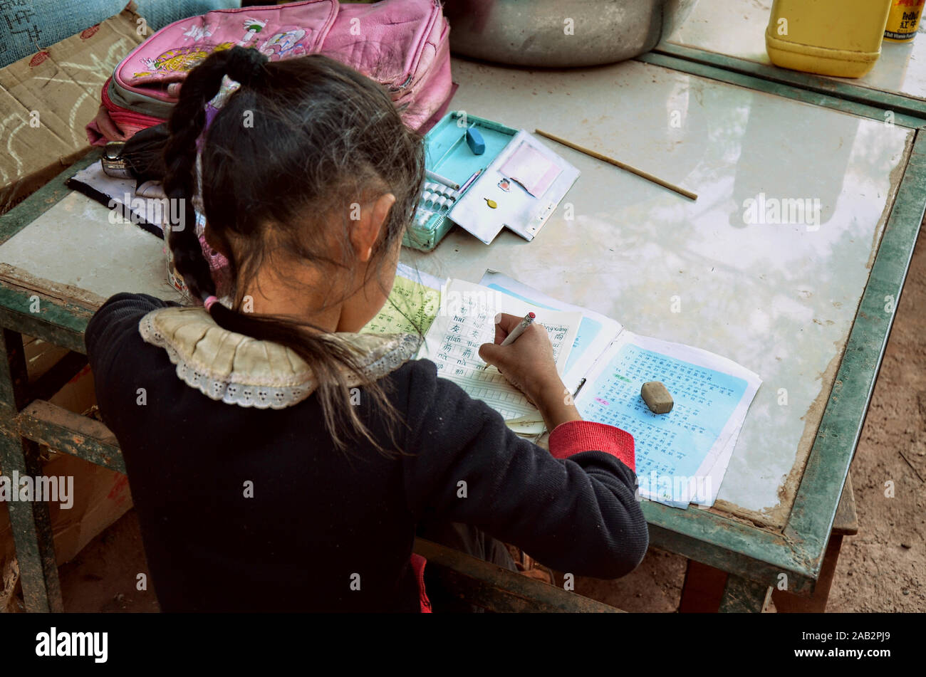 Lavorare sodo. Ragazza della scuola che fa i compiti nel villaggio di Nuodeng, provincia di Yunnan, Cina. Foto Stock