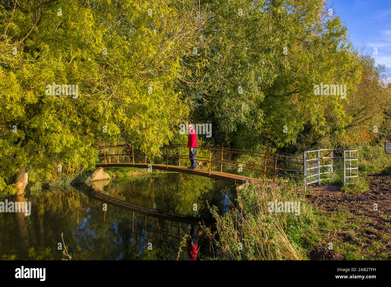 Un uomo e il suo cane mettere in pausa su una passerella a Baldry's Mill che attraversano il fiume Waveney a Bungay comune. Inizio degli angoli strada a piedi. Foto Stock