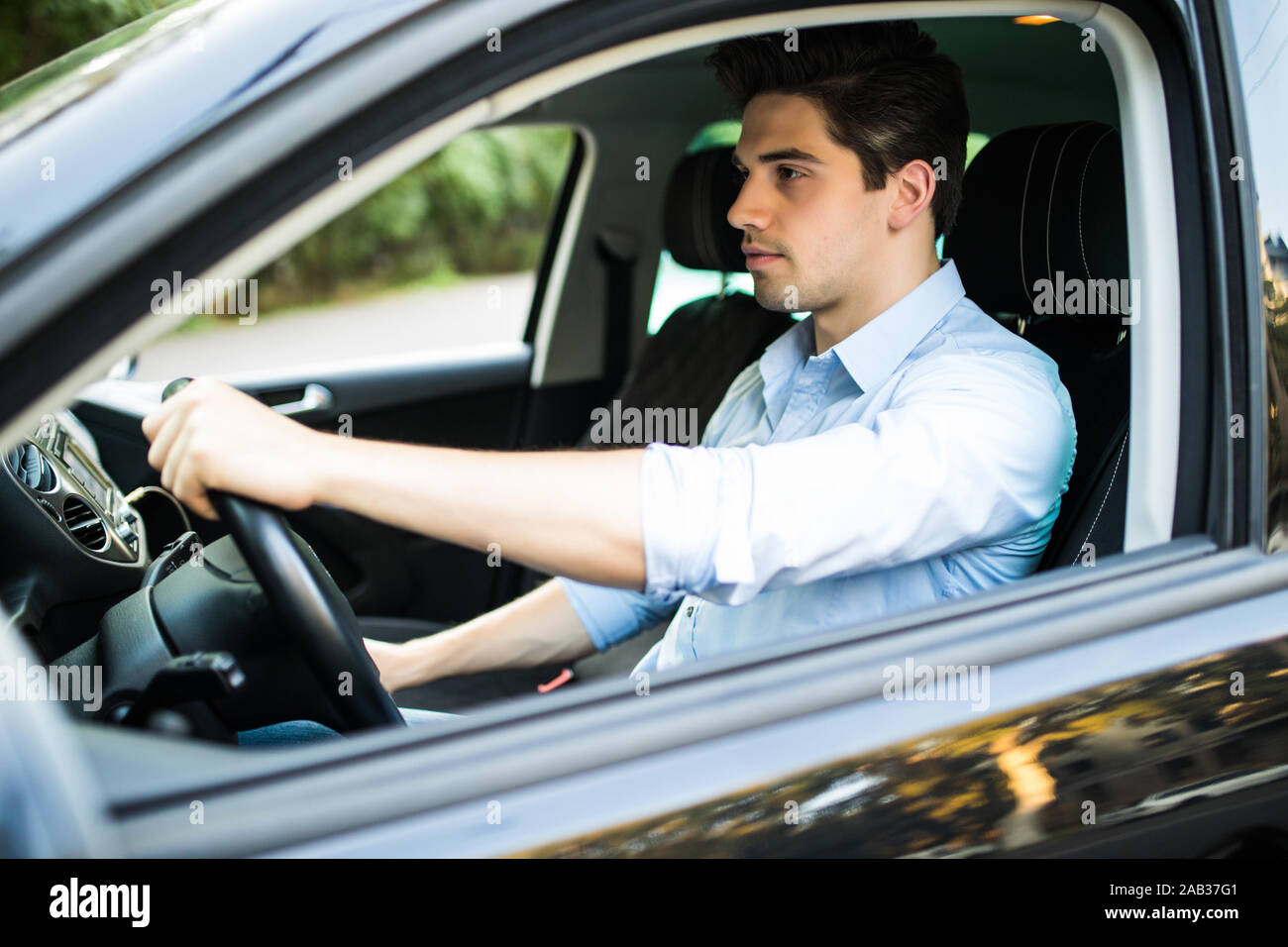Ritratto di un bel ragazzo alla guida della sua auto Foto Stock
