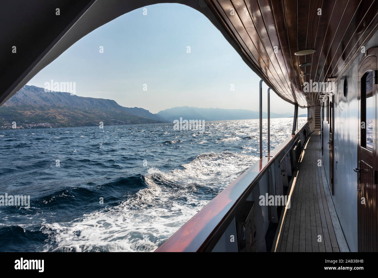 Bella vista sul mare Adriatico con le isole e il sole sparato dal ponte a bordo di una barca con dettagli in legno. Le onde in acqua, vista Foto Stock