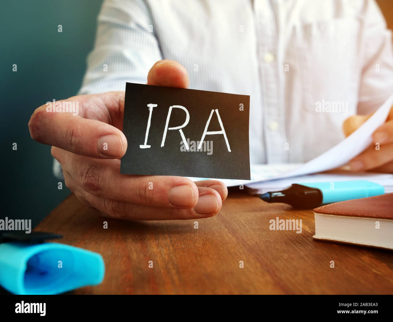 L'uomo individuale tiene conto pensione IRA segno sul foglio nero. Foto Stock
