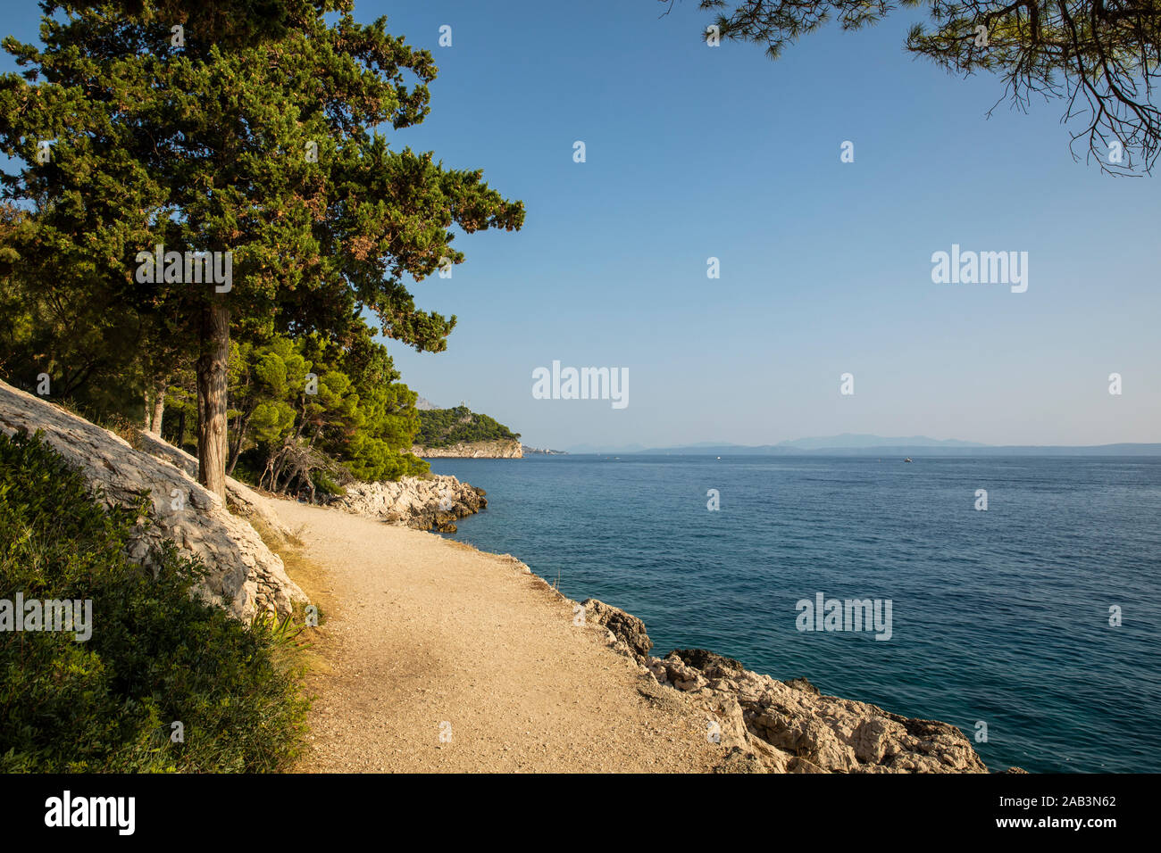 Makarska in Dalmazia, Croazia. Vista dalla penisola in una giornata di sole in estate con un cielo blu. Un percorso nella natura ruvida con verde, alberi, rock Foto Stock