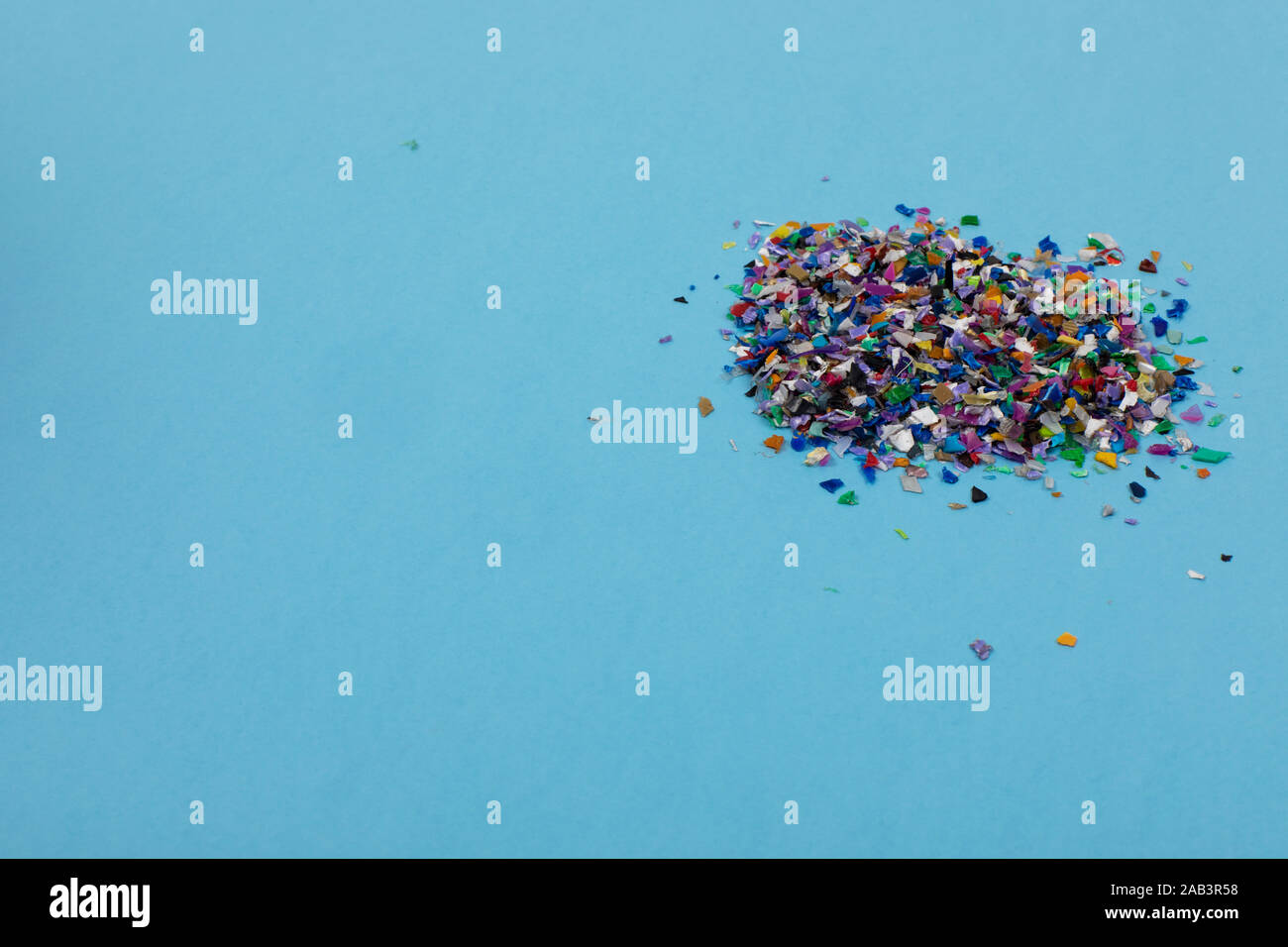 Frantumato circolare palline di plastica, parti realizzate multicolore di plastica riciclata raccolte in mare flatlay su uno sfondo blu pronto per essere usato per nuovo Foto Stock