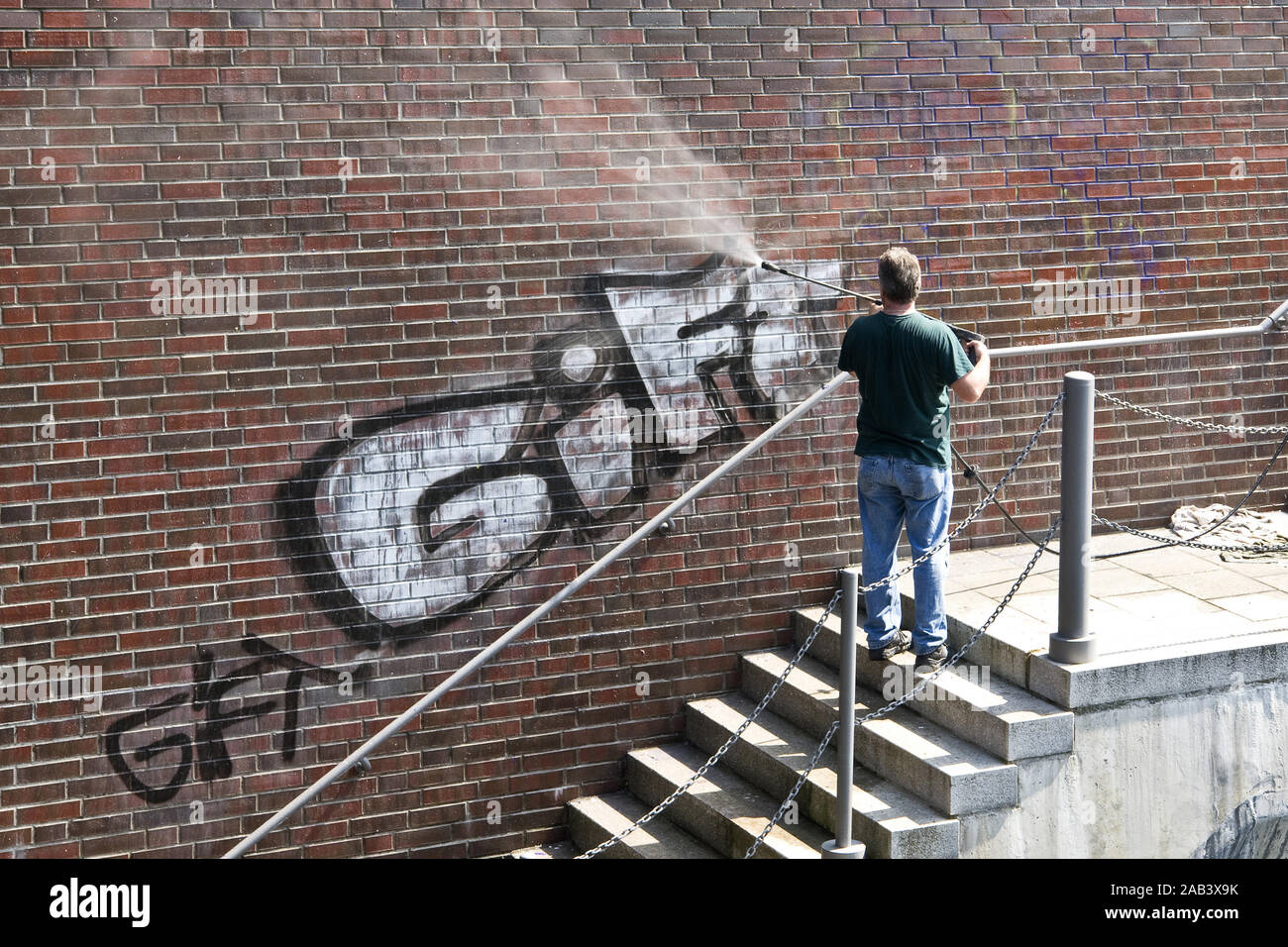 Mann entfernt Graffiti un einer Mauer |uomo rimosso graffiti su un muro| Foto Stock
