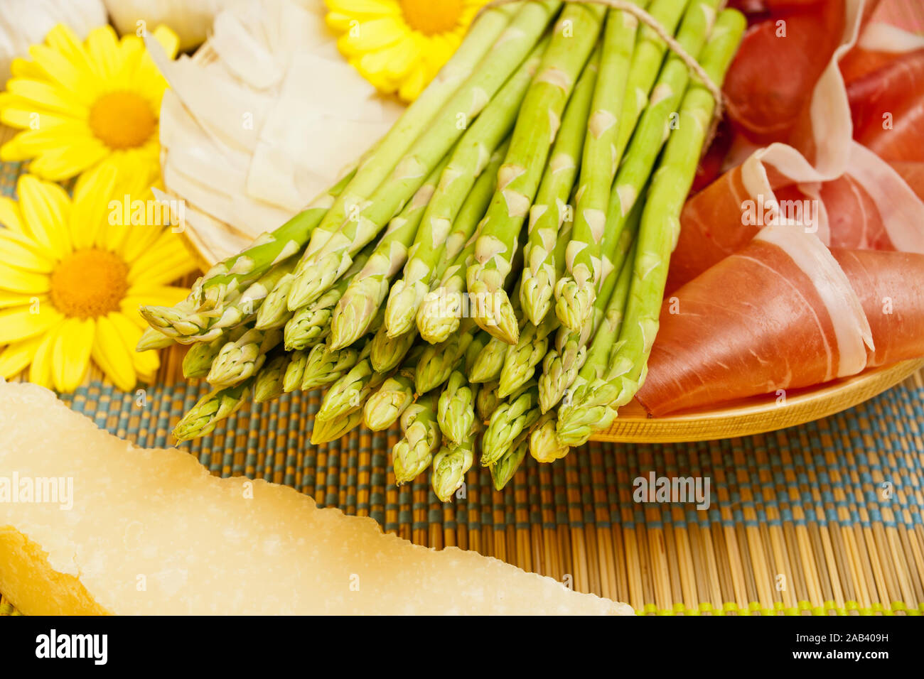 Grüner Spargel in einer Holzschale zusammen mit Schinken und Parmesan |asparago verde in una ciotola di legno con prosciutto e formaggio parmigiano| Foto Stock