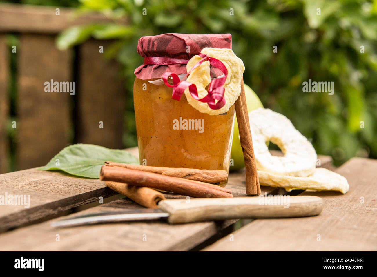Ein Glas mit Apfelkonfitüre mit Zimtstangen auf einer Obstkiste |Un bicchiere di marmellata di mele con bastoncini di cannella su una cassetta da frutta| Foto Stock