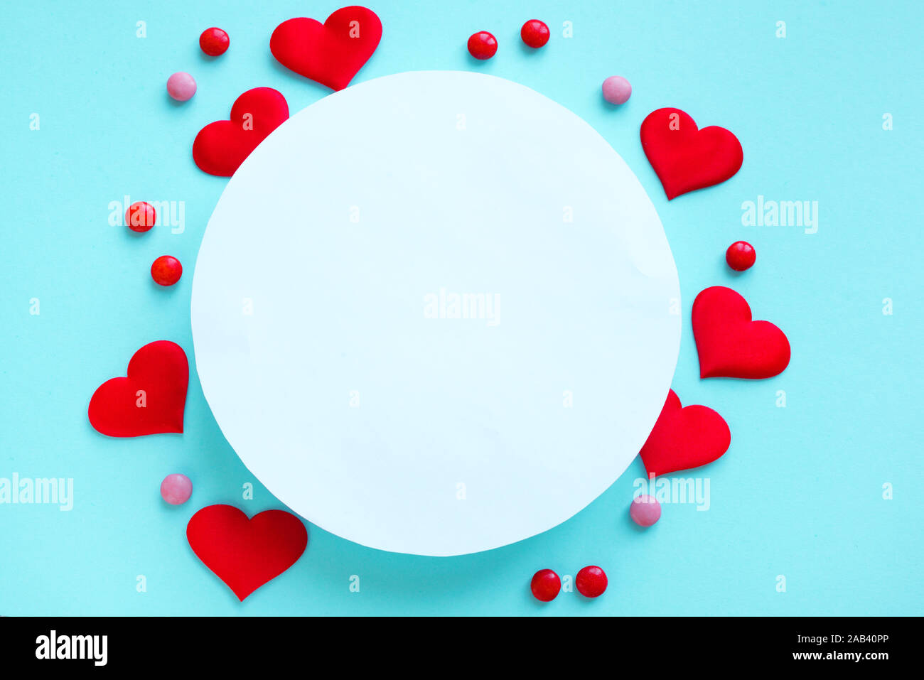 Il giorno di San Valentino sfondo. Cuori rossi e caramelle sul pastello blu sfondo con round copia spazio. Il giorno di San Valentino, amore, il concetto di matrimonio. Piatto, laici t Foto Stock