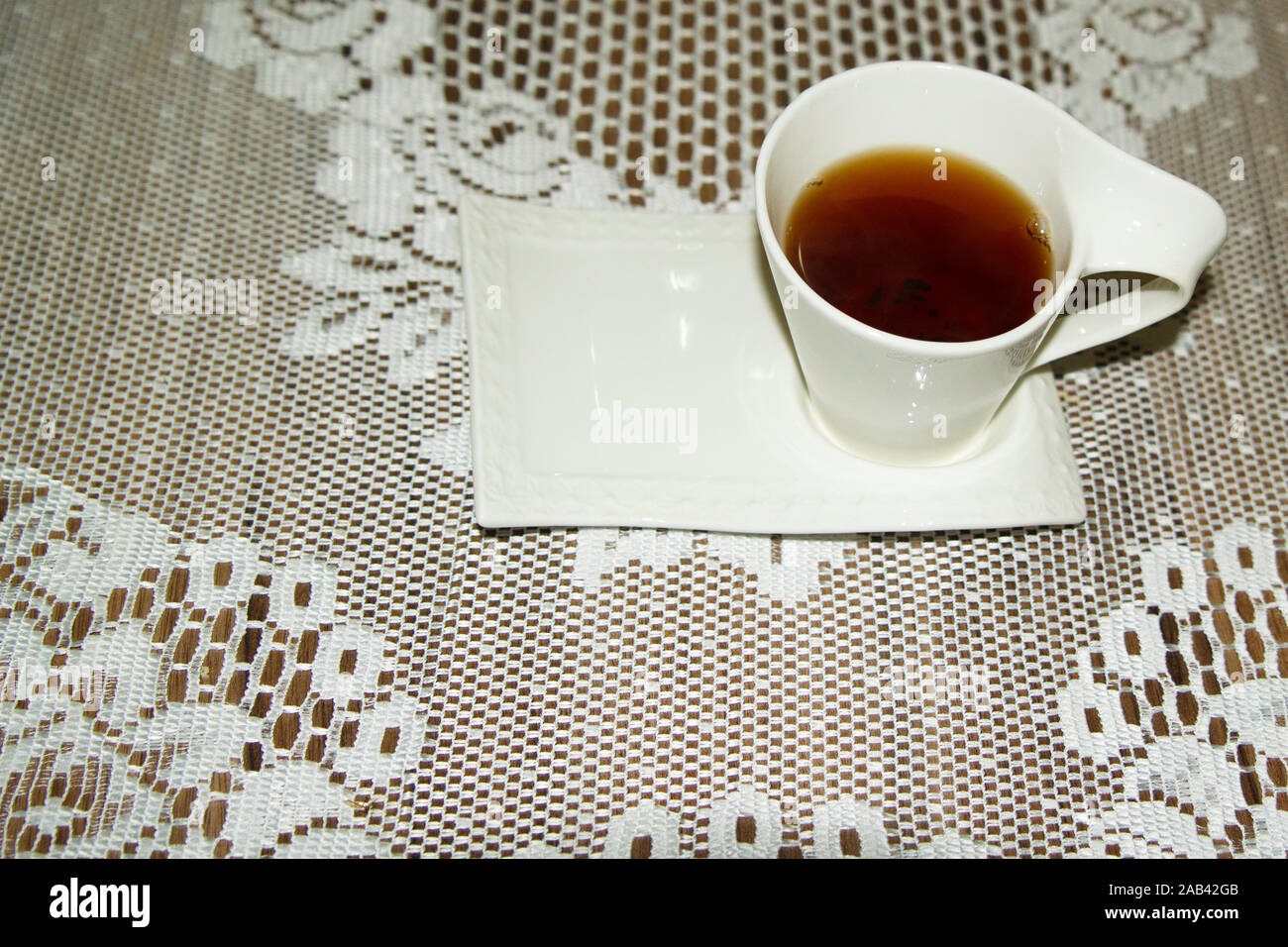 Tè nero in tazza bianca su una tovaglia di pizzo bianco Foto Stock