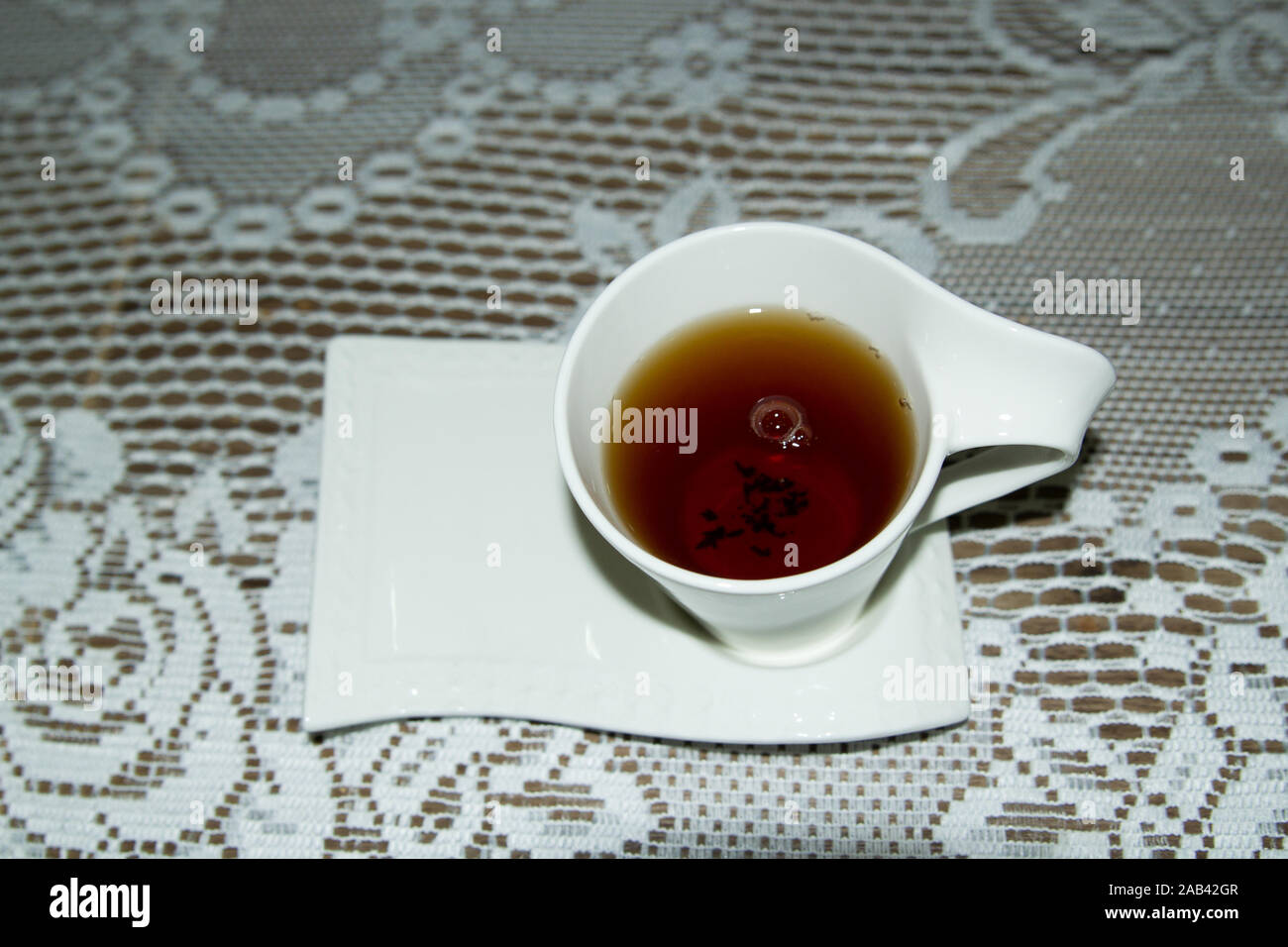 Tè nero in tazza bianca su una tovaglia di pizzo bianco Foto Stock