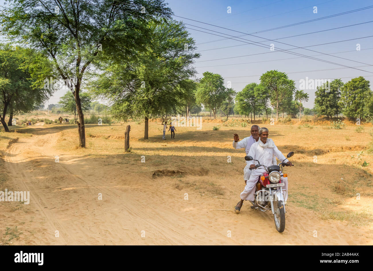 Due uomini su una motocicletta su una strada sterrata in Rajasthan, India Foto Stock