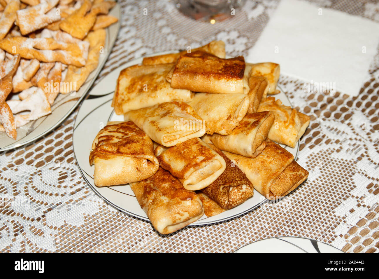 Frittelle fritte con ripieno interno su un piatto bianco su un tavolo con una tovaglia di pizzo bianco. Foto Stock