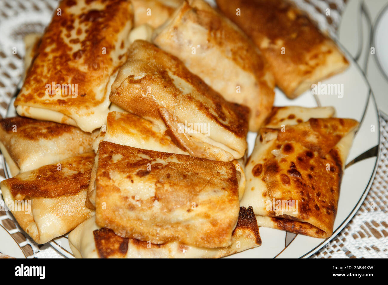 Frittelle fritte con ripieno interno su un piatto bianco su un tavolo con una tovaglia di pizzo bianco. Foto Stock
